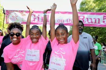 Two GOTR girls and Running Buddy looking at the camera celebrating at the 5K finish line